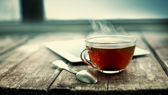 A cup of tea is on a wooden table